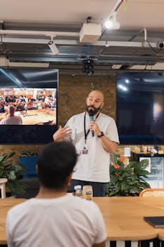 A speaker delivers a presentation in a modern office with an attentive audience.